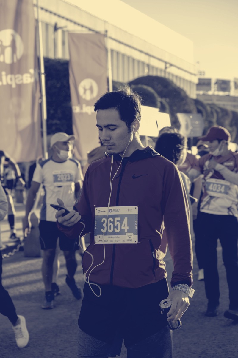 Runner with earbuds checking the app before a marathon