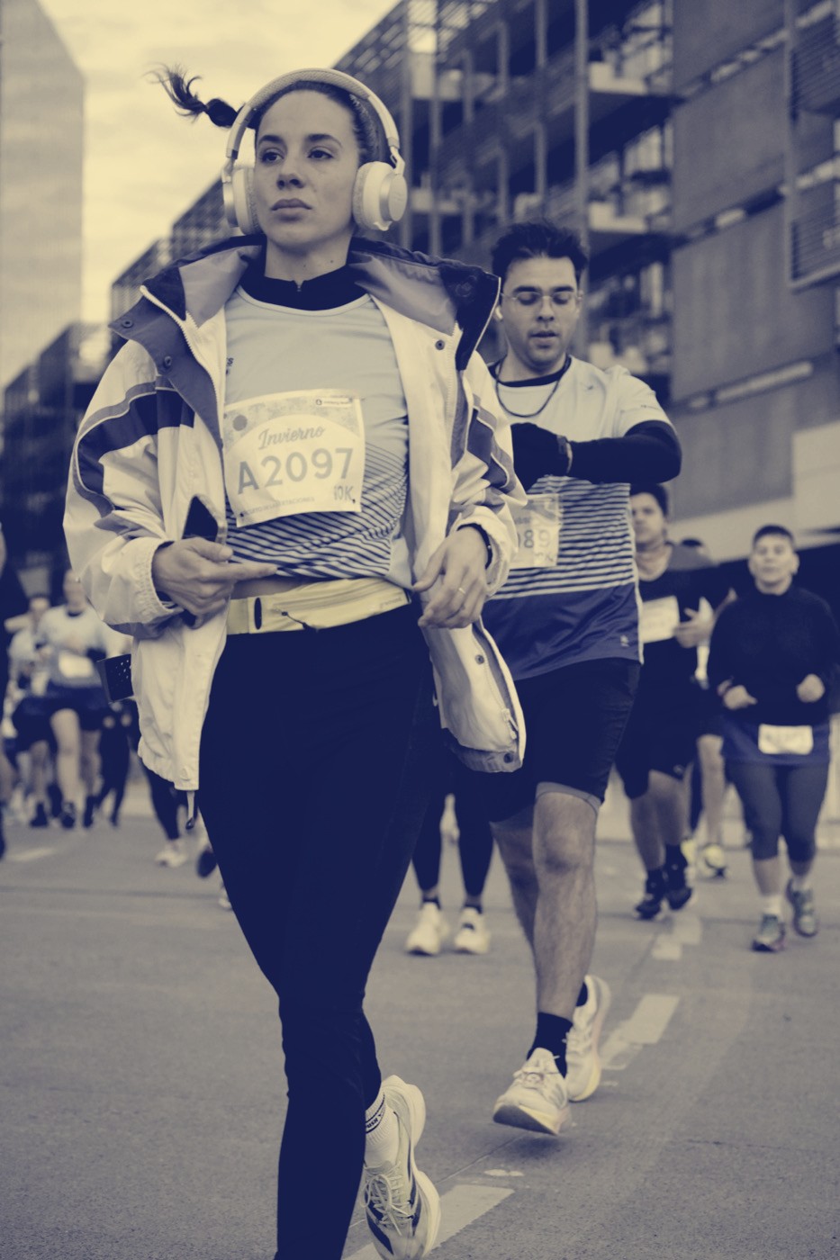 Runner wearing headphones during a race, checking her phone